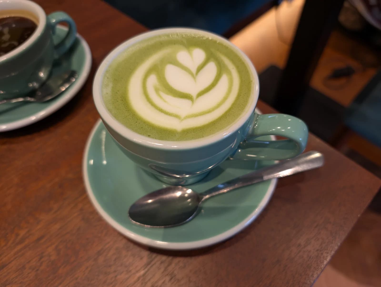 Green matcha latte with milk-foam latte art in a blue cup
