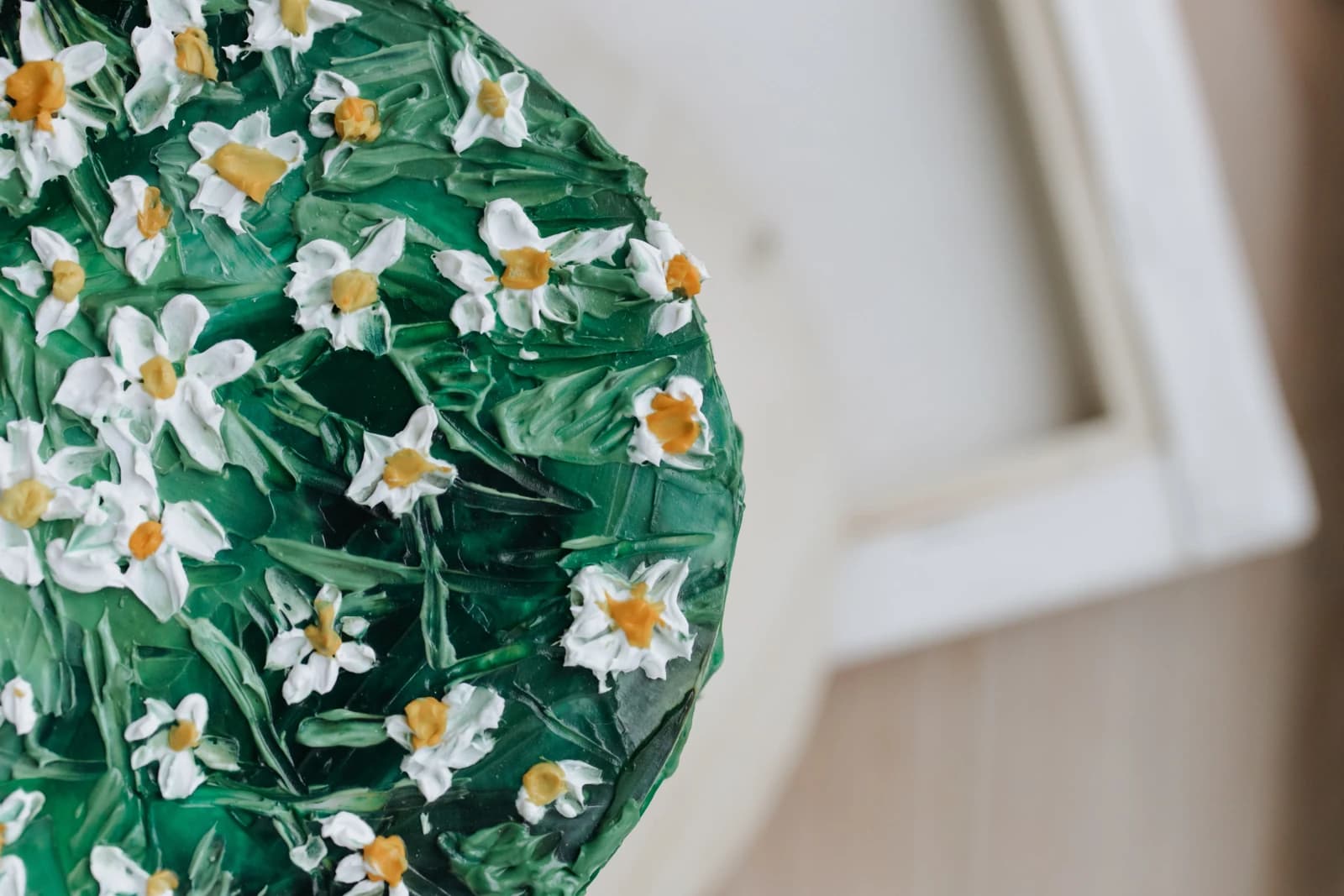 Green textured cake covered with small white daisies and yellow centers.