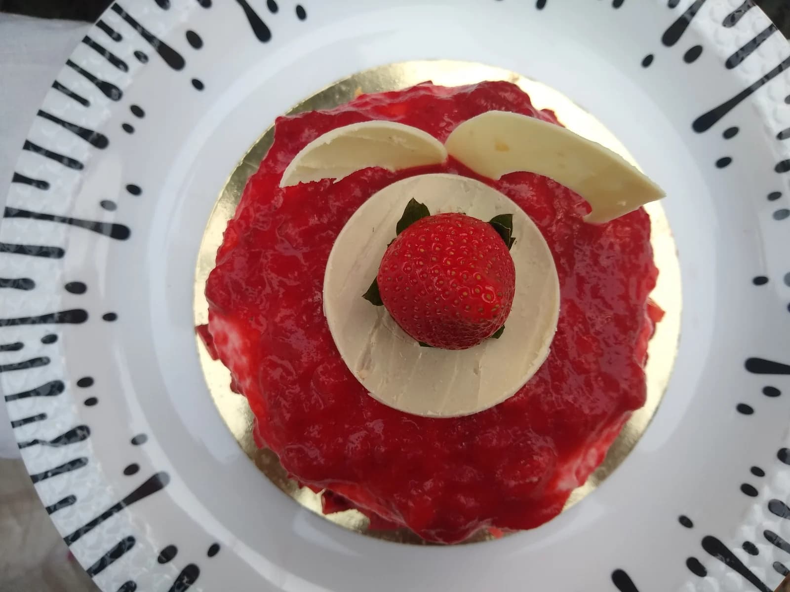 Top view of a strawberry-topped cheesecake with white decorative petals