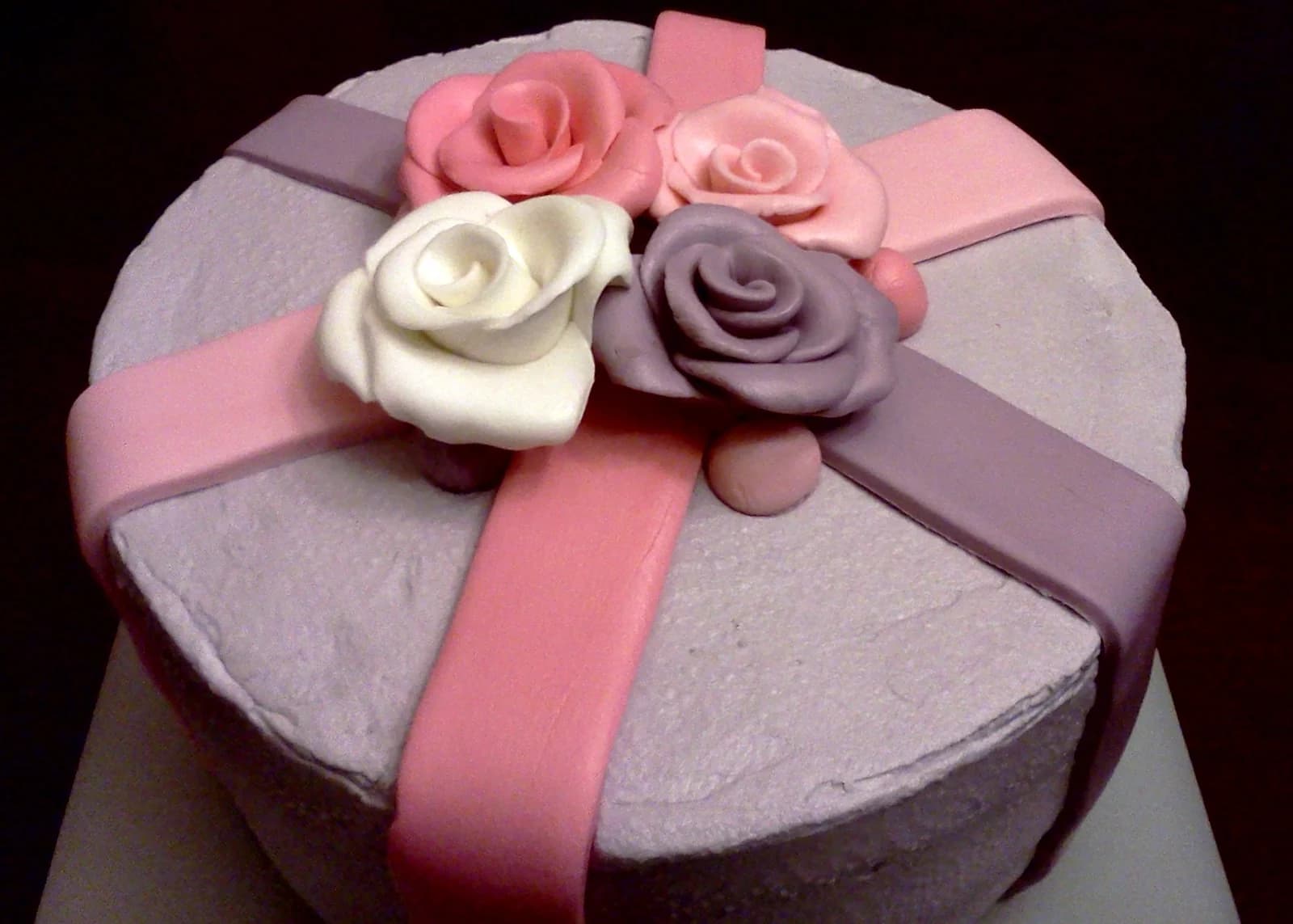 Lilac cake with pink ribbon decoration and pink, white and purple roses