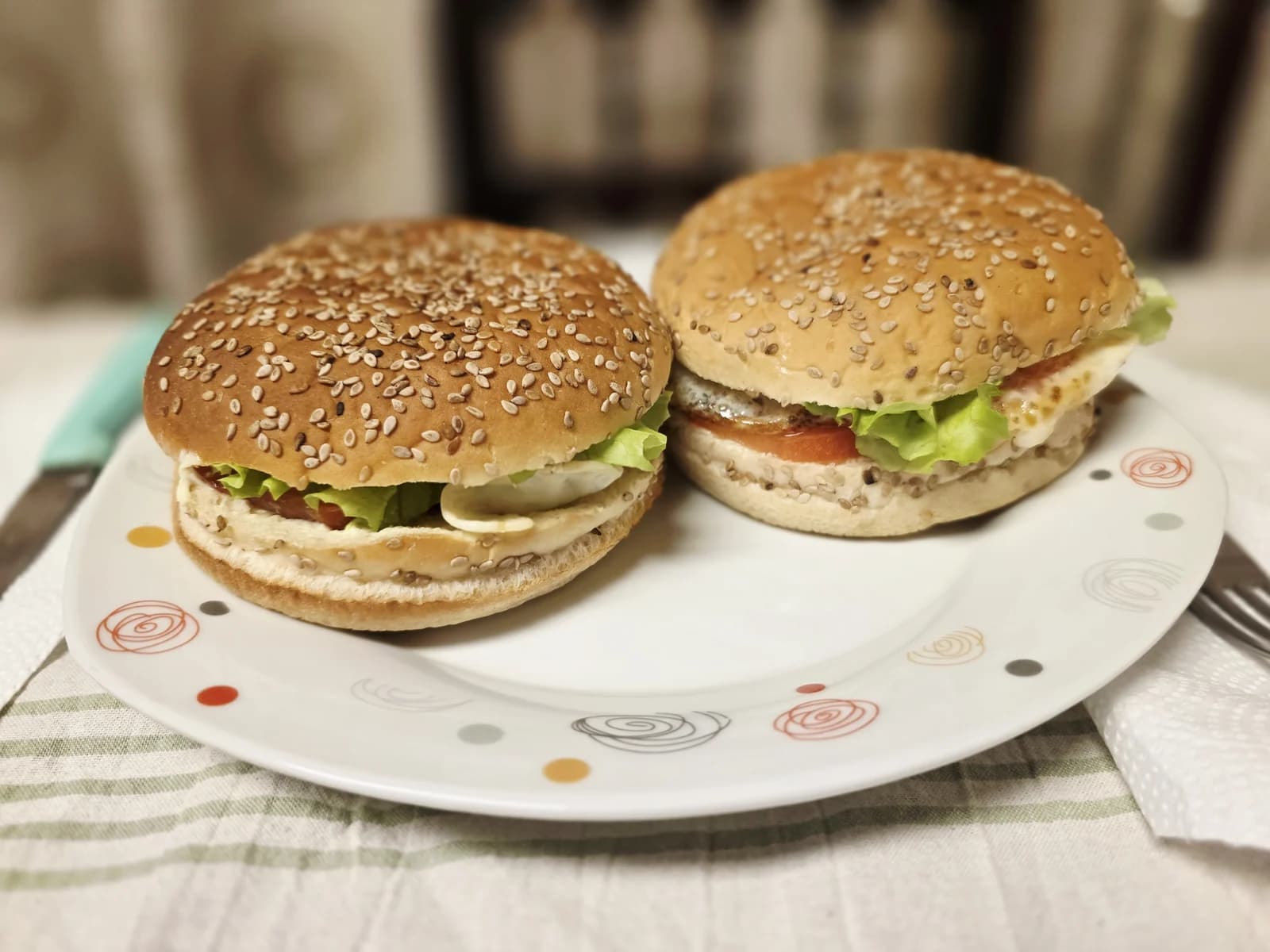 Two homemade sesame-bun burgers resting on food paper