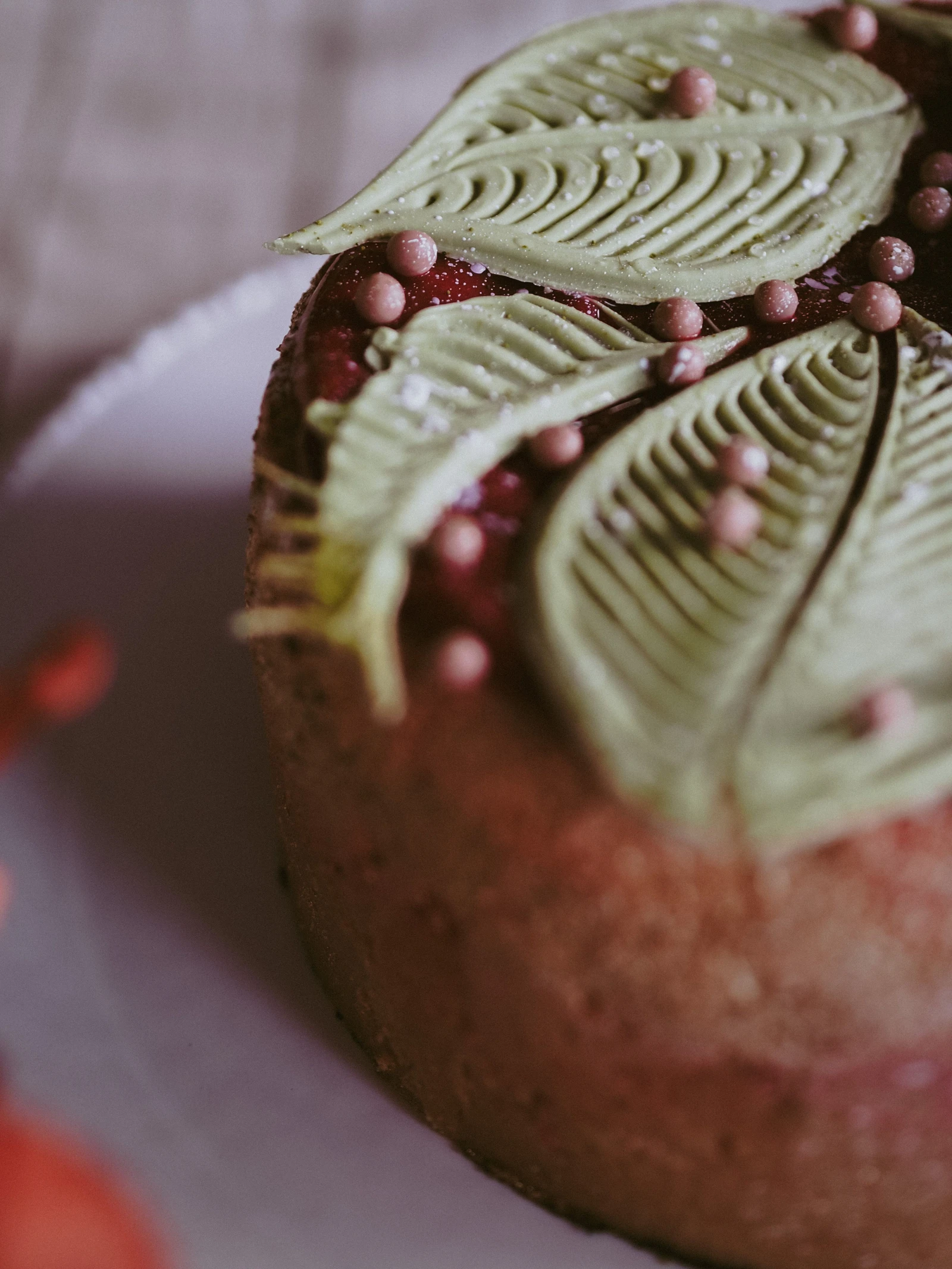 Close view of a brown cake topped with large pale green veined fondant leaves.