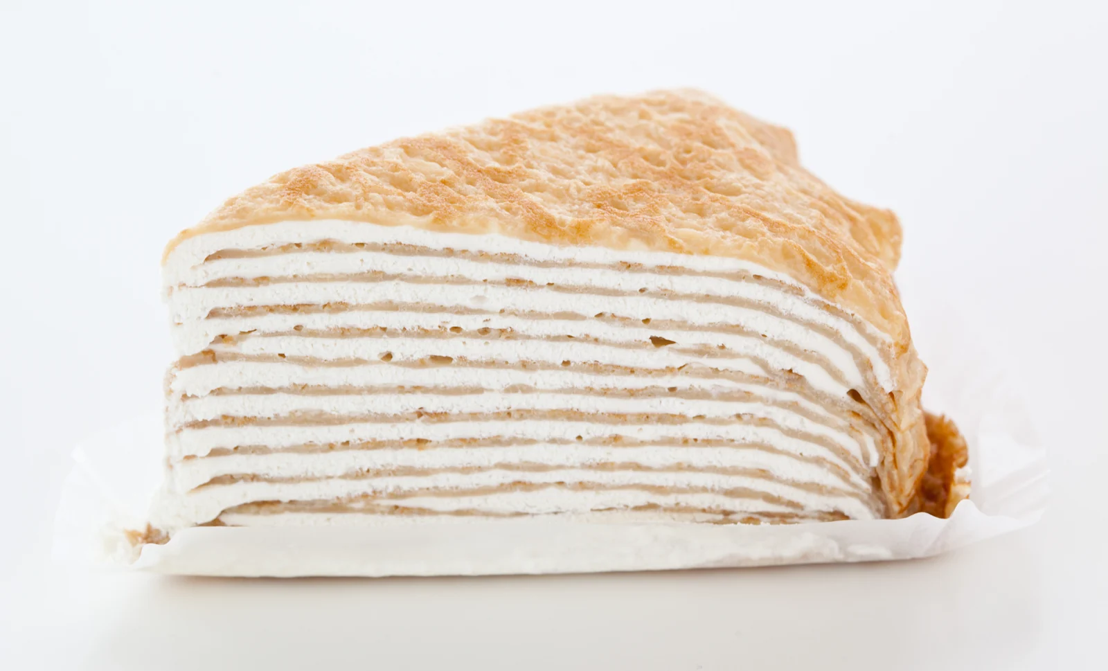 A slice of mille-crepe cake showing many thin crepe and cream layers