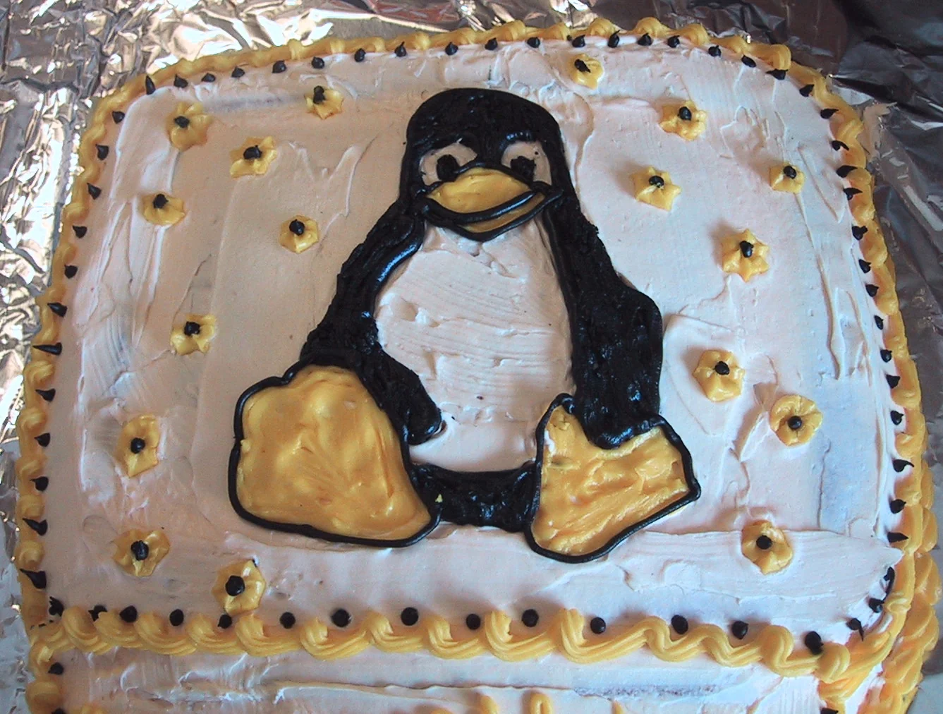 Rectangular birthday cake with an iced Linux Tux penguin and piped stars