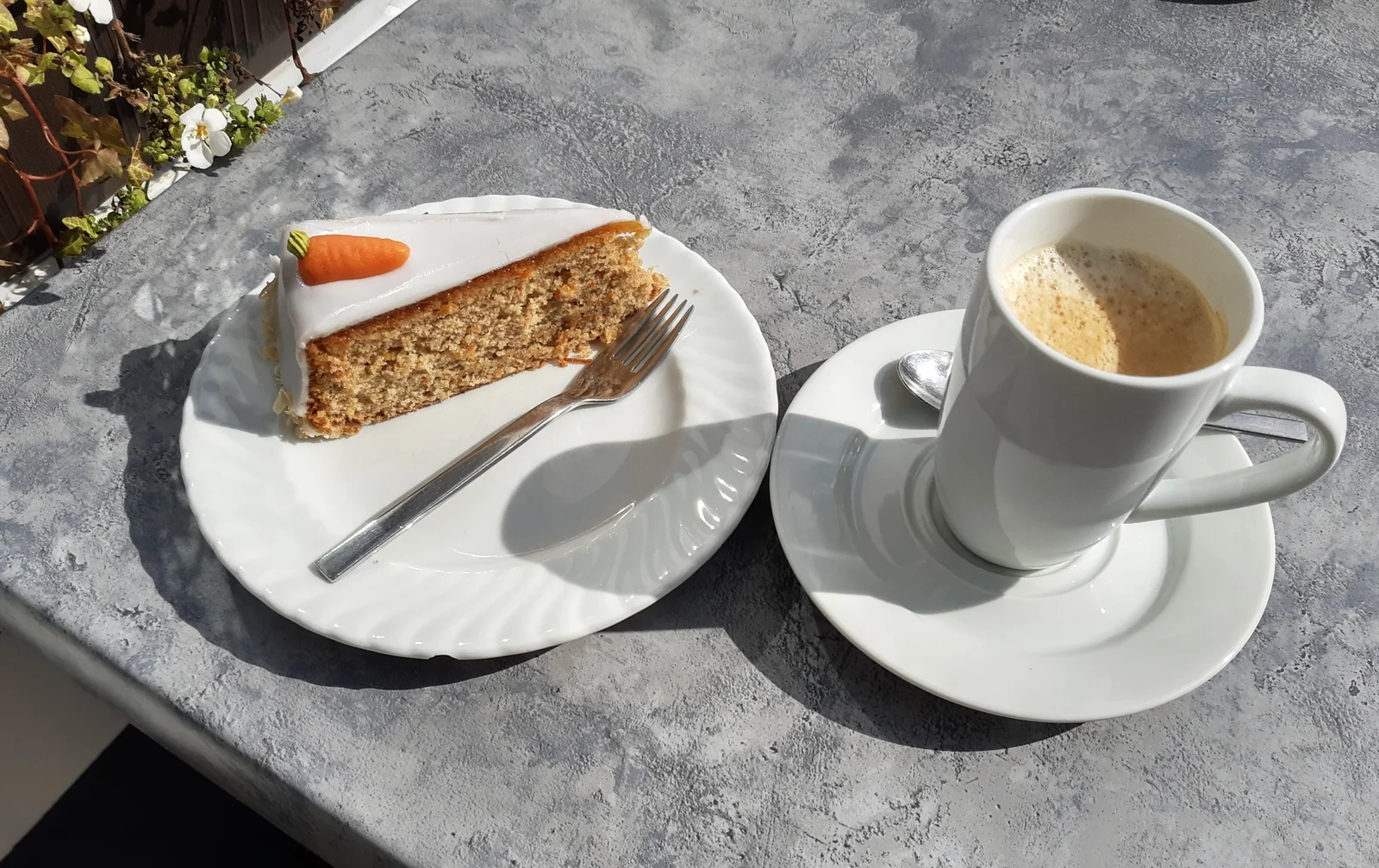 Carrot cake slice with white frosting and a small carrot decoration