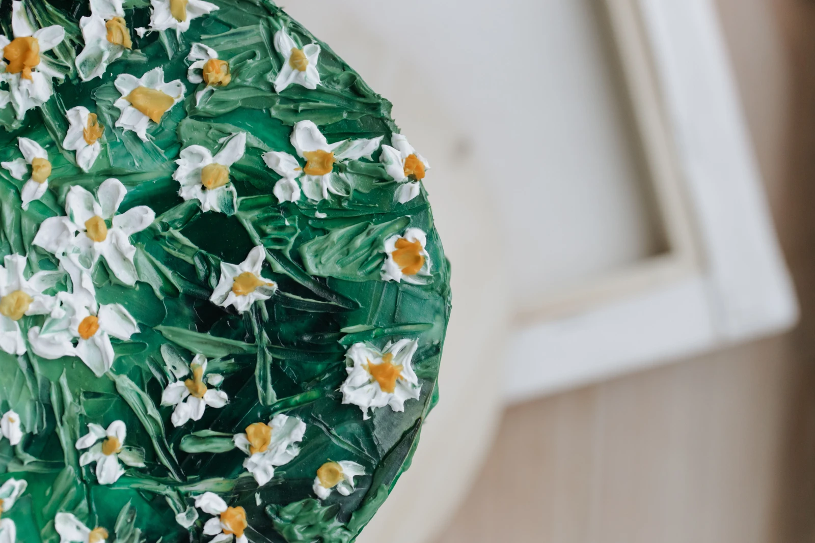Green textured cake covered with small white daisies and yellow centers.