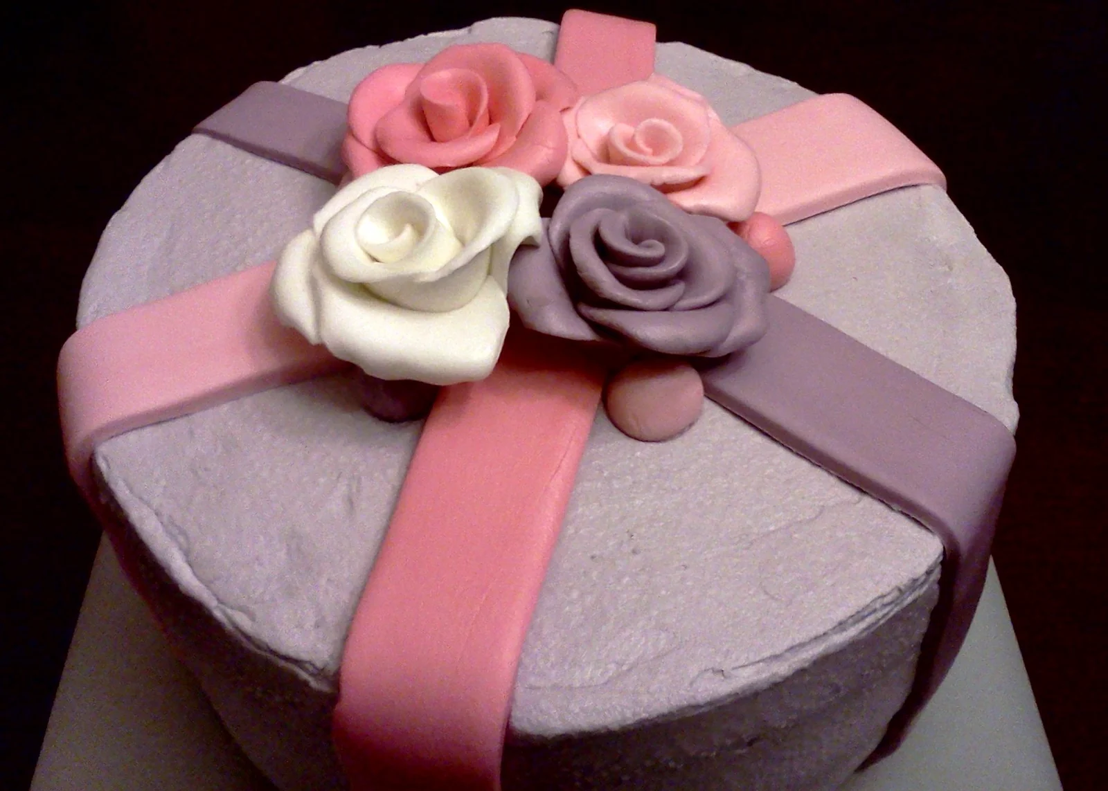 Lilac cake with pink ribbon decoration and pink, white and purple roses